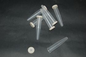 Several transparent, conically shaped tubes with a white rim lie on a dark background. A single rim lies separately next to it. The tubes are cut flower tubes.