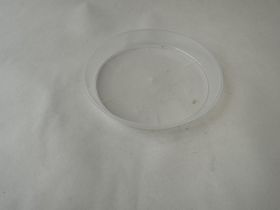 Un dessous de verre en plastique transparent vide est posé sur une surface blanche légèrement structurée.
