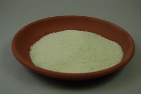 Eine braune Schale ist mit einem hellen, körnigen Material gefüllt. Die Schale steht auf einer grauen Oberfläche.