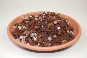 A shallow, orange-coloured bowl filled with a mixture of brown pieces of wood and small white particles.