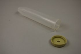 A transparent plastic tube lies next to a round, yellow lid with a hole in the middle on a grey surface.