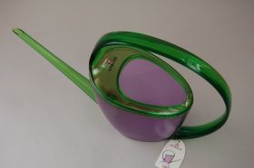 Un arrosoir violet avec une poignée et un bec verseur verts. L'arrosoir a une forme ovale, la poignée est incurvée. Une étiquette de la marque Scheurich y est accrochée.